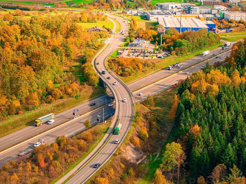 Traffic on a road junction in an autumnal wooded area with blooming landscape, A8 near Rutesheim, Germany