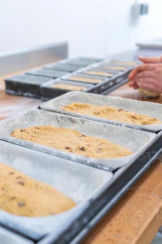 Dough in loaf pans, hands of a baker working dough in the background, Christmas baking, Haselstaller Hof, Wildberg, Germany