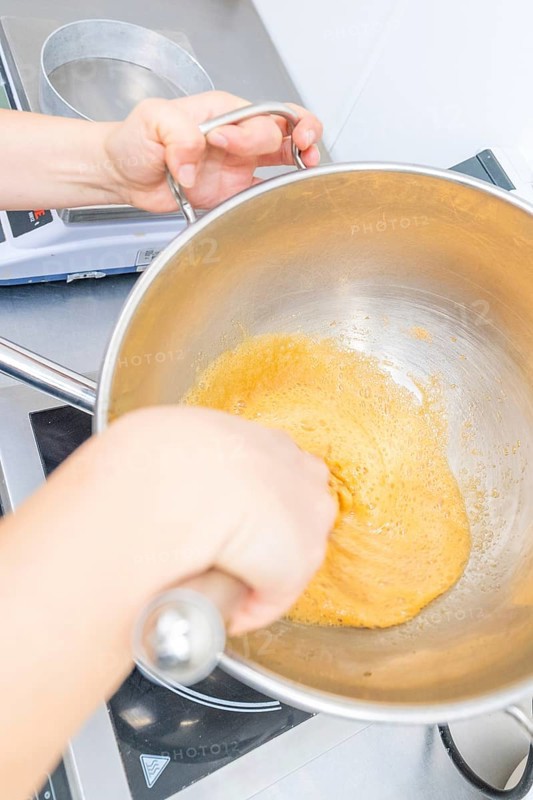 A person is stirring a yellow dough in a pan on a stove, Christmas baking, Haselstaller Hof, Wildberg, Germany