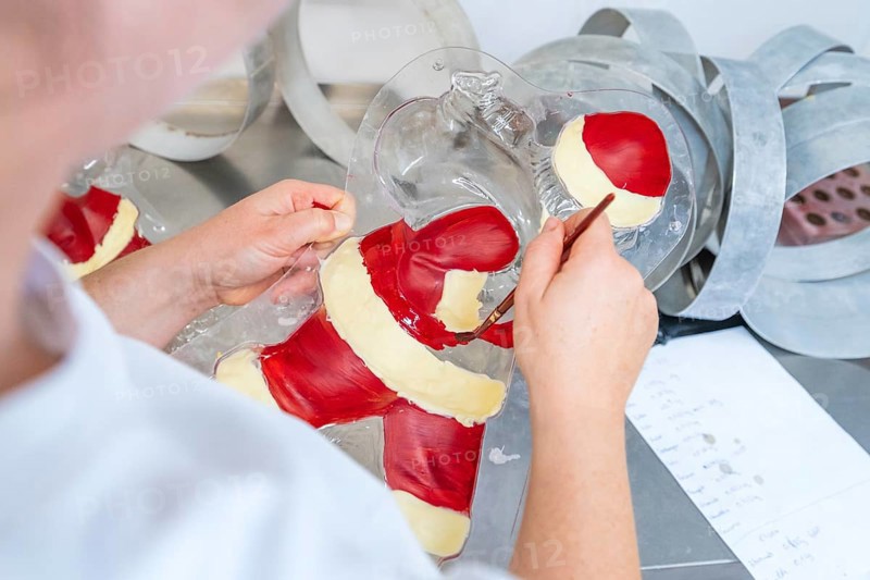 A person paints details in a chocolate Santa Claus mold, Christmas baking, Haselstaller Hof, Wildberg, Germany