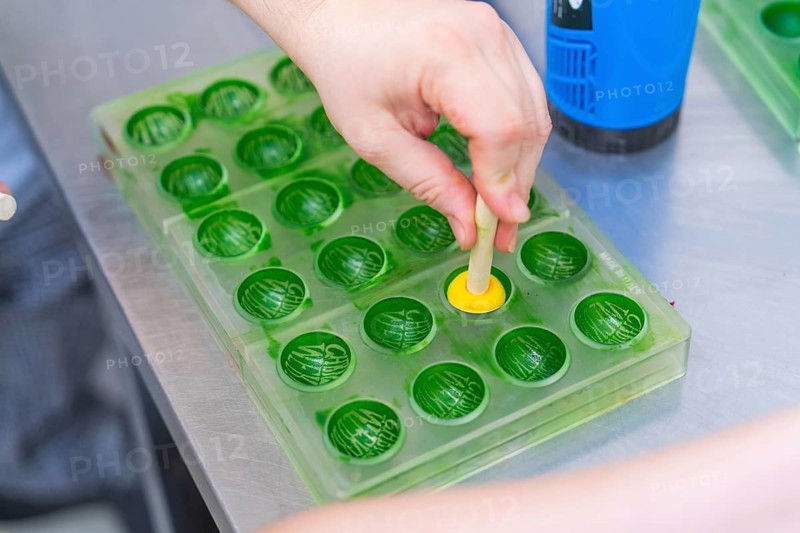 A hand forms a praline in a green chocolate mold, Christmas baking, Haselstaller Hof, Wildberg, Germany