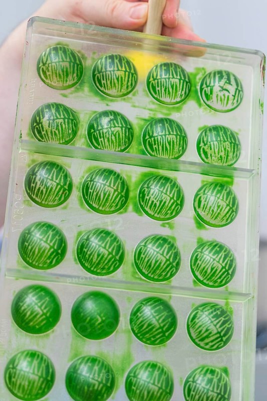Green chocolate mold with the text 'Merry Christmas' in a chocolate workshop, Weihnachtsbacken, Haselstaller Hof, Wildberg, Germany