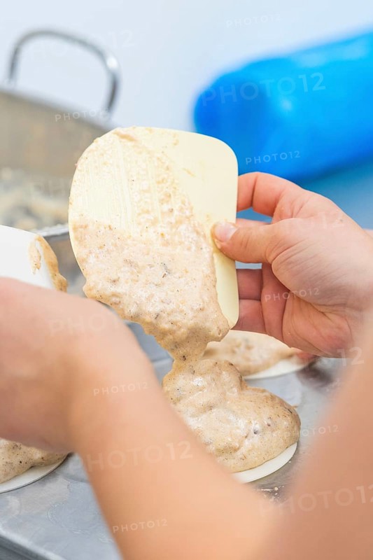 Dough is held by one hand with a silicone spatula and poured into a mold, Weihnachtsbacken, Haselstaller Hof, Wildberg, Germany