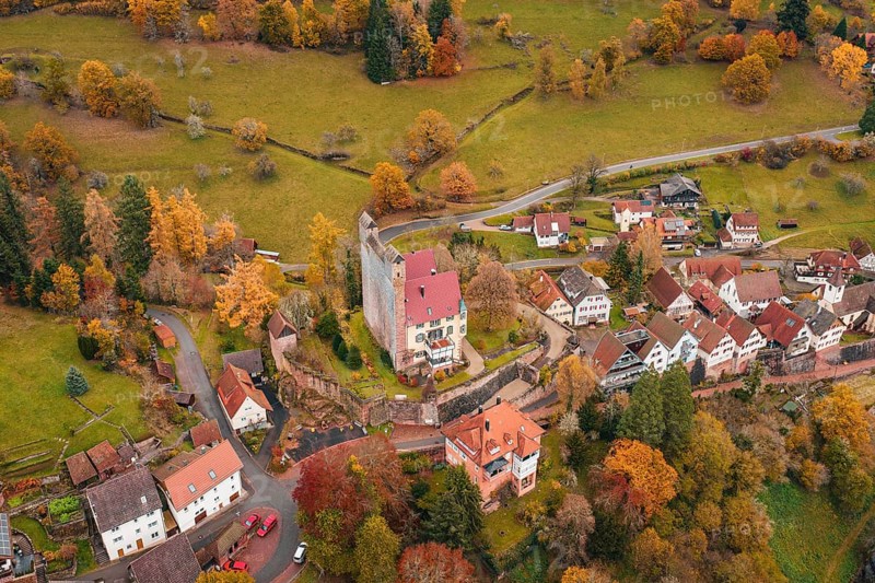 A historic castle towers over an autumnal village in extensive meadows, Berneck Castle, Altentsteig, Calw District, Germany