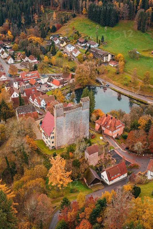 A castle next to a river in the middle of an autumn-colored village, Berneck Castle, Altentsteig, Calw district, Germany
