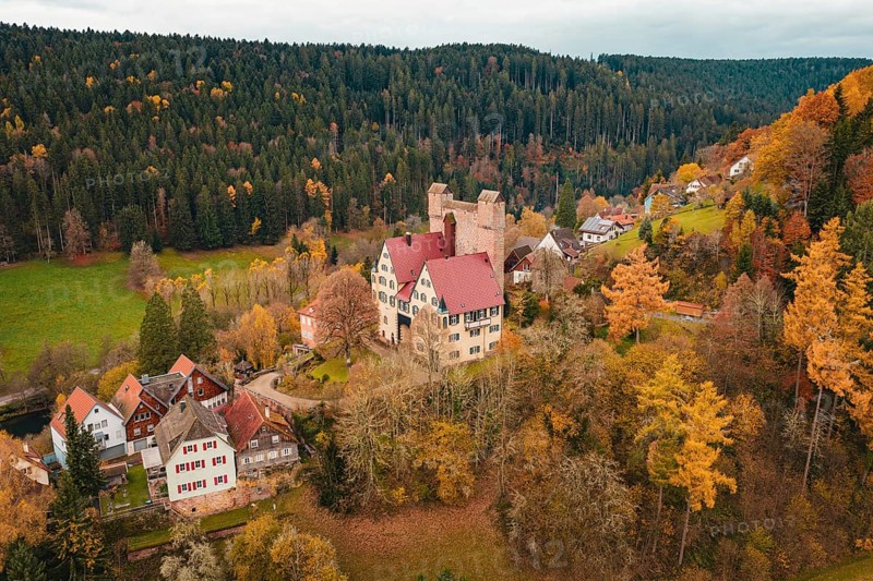 A castle and a small village nestled in an autumn forest landscape, Berneck Castle, Altentsteig, Calw district, Germany