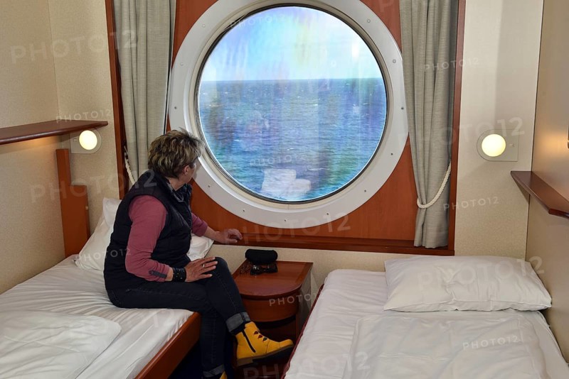 Woman looking out of her ship cabin at the sea, Baltic Sea, Color Line ferry, Schleswig-Holstein, Germany