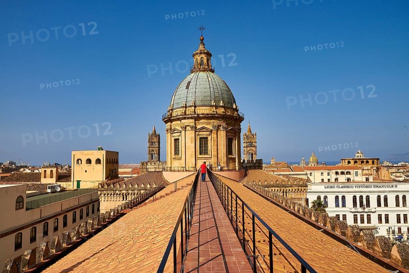 A person walks on a roof in Palermo to the historic dome with clear sky in the background, Palermo, Cathedral, UNESCO World Heritage Site, Sicily, Italy