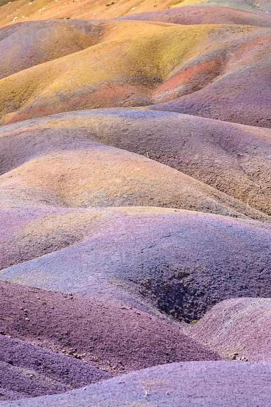 Colourful wavy hills that form a surreal pattern in yellow, purple and orange. Africa, East Africa, Mauritius, Chamarel, Seven Coloured Earth