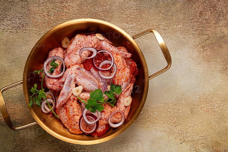 Chicken wings, in a brass saucepan, ready for cooking, grilling or baking, in a home kitchen, no people