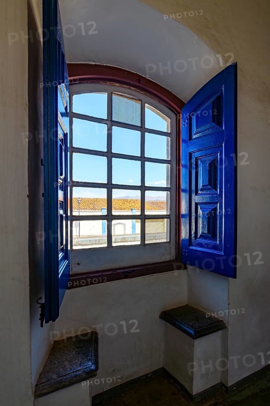 Colonial house in the city of Congonhas seen through the window of a historic Baroque church, Congonhas, Minas Gerais, Brazil