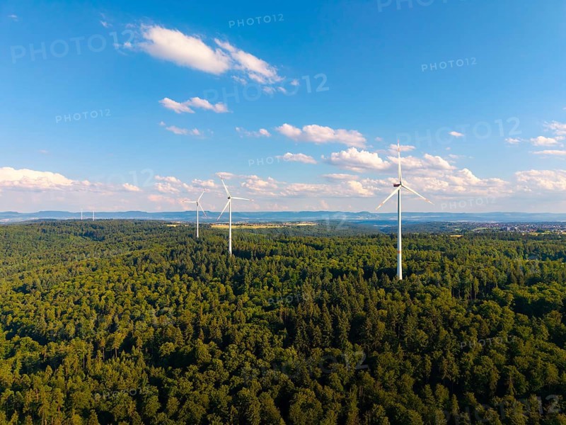 Several wind turbines rise above a lush forest under a sky with light clouds, near Schorndorf, Rems-Murr-Kreis, Baden-Württemberg, Germany