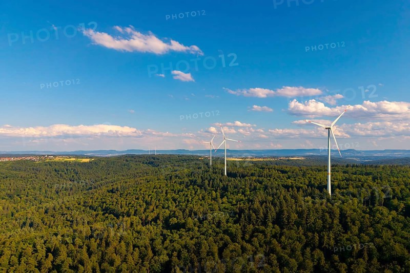 Wind turbines over a thick forest under a clear blue sky with some clouds, near Schorndorf, Rems-Murr-Kreis, Baden-Württemberg, Germany