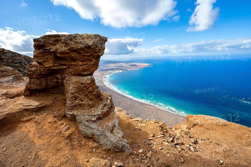 Distinctive rock on the cliffs, view from the Risco de Famara cliffs to Famara beach, Playa de Famara with La Calaeta, Lanzarote, Canary Islands, Spain