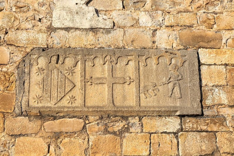 Religious stonework imagery on church wall, Echo or Hecho, Valle de Hecho, Pyrenees Mountains, Huesca province, Aragon, Spain