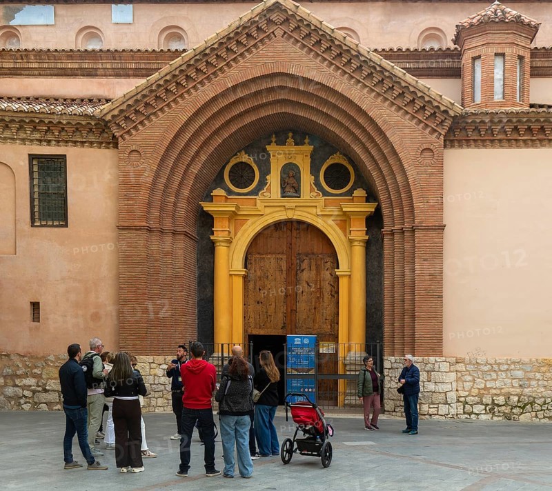Tour guide and group of people outside Mudéjar door of cathedral church building, city centre of Teruel, Aragon, Spain