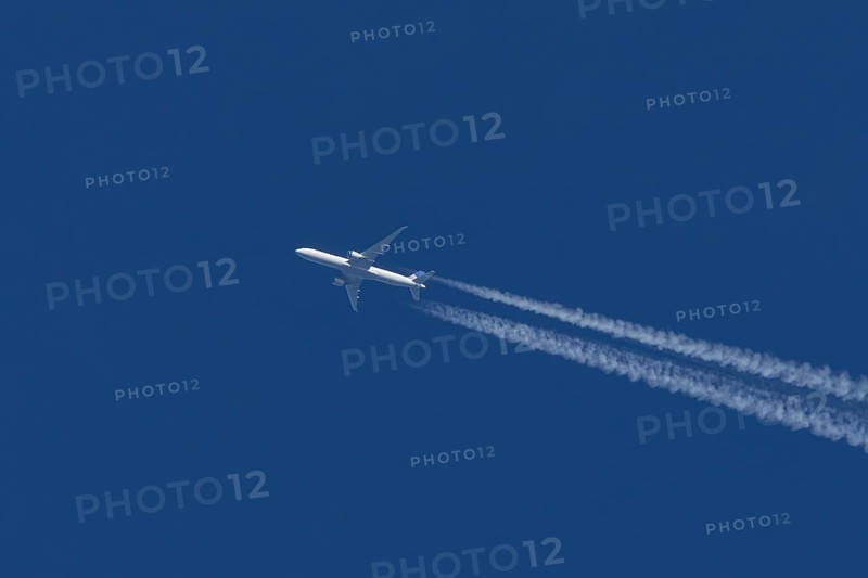 Boeing jet passenger aircraft of United airways airlines flying in a blue sky with contrails or vapour trails behind, England, United Kingdom