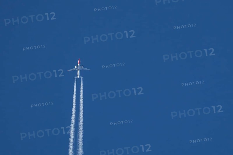 Boeing 737 jet passenger aircraft of Norwegian Air airlines flying in a blue sky with contrails or vapour trails behind, England, United Kingdom