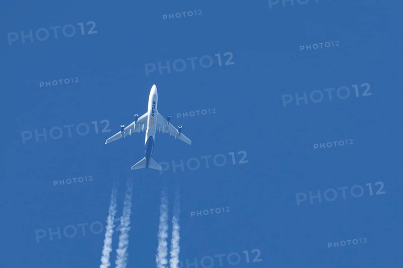 Boeing 747 jumbo jet cargo aircraft of Atlas air airlines flying in a blue sky with contrails or vapour trails behind, England, United Kingdom