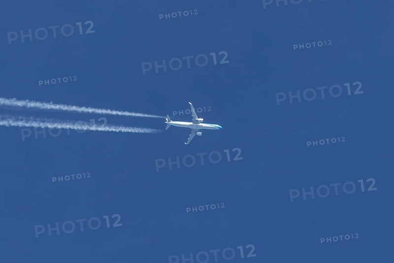 Jet passenger aircraft flying in a blue sky with contrails or vapour trails behind, England, United Kingdom