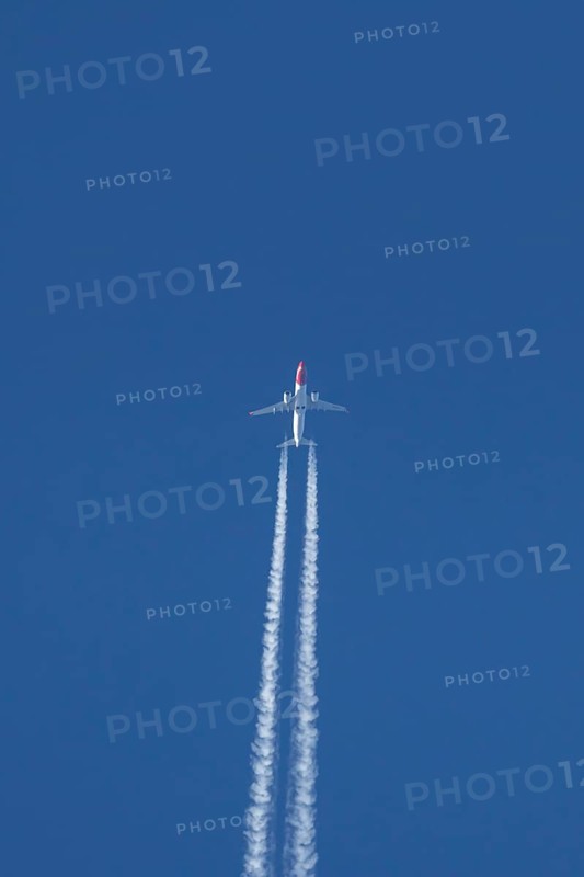 Boeing 737 jet passenger aircraft of Norwegian Air airlines flying in a blue sky with contrails or vapour trails behind, England, United Kingdom