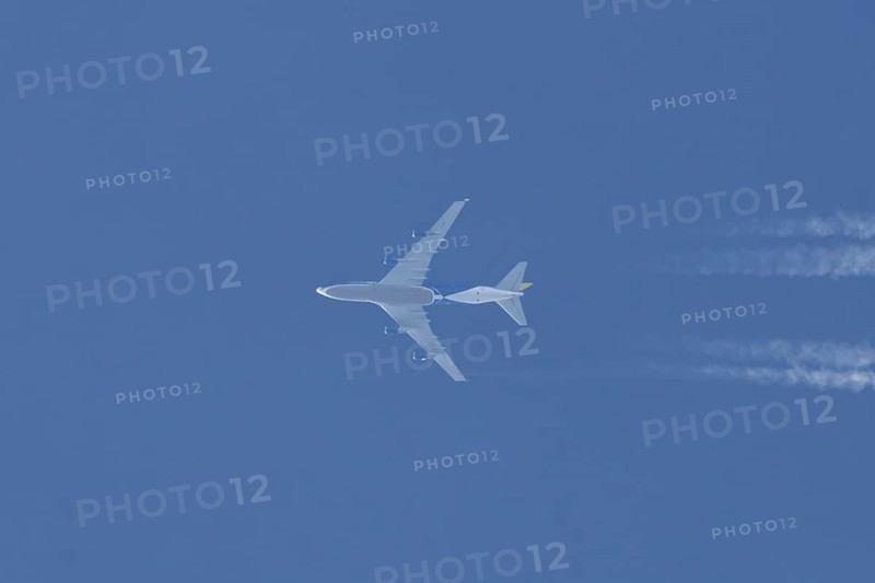 Boeing 747 jumbo jet cargo aircraft flying in a blue sky with contrails or vapour trails behind, England, United Kingdom