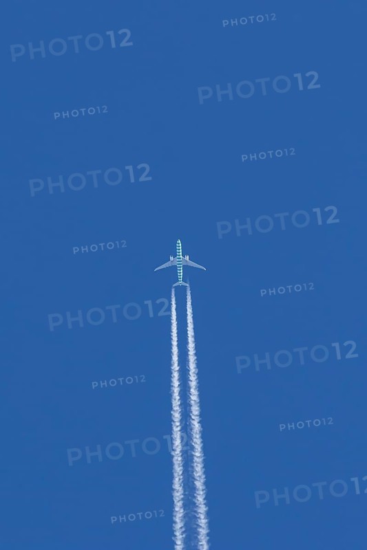 Boeing jet passenger aircraft flying in a blue sky with contrails or vapour trails behind, England, United Kingdom