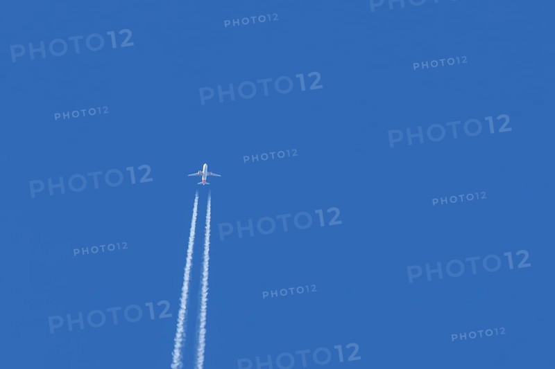 Airbus jet passenger aircraft of Easyjet airlines flying in a blue sky with contrails or vapour trails behind, England, United Kingdom