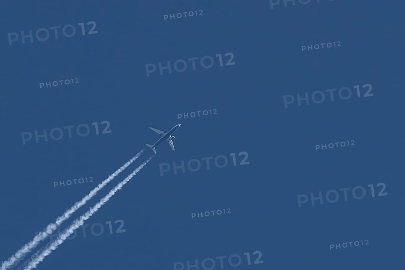 Boeing 737 jet passenger aircraft of Ryanair airlines flying in a blue sky with contrails or vapour trails behind, England, United Kingdom
