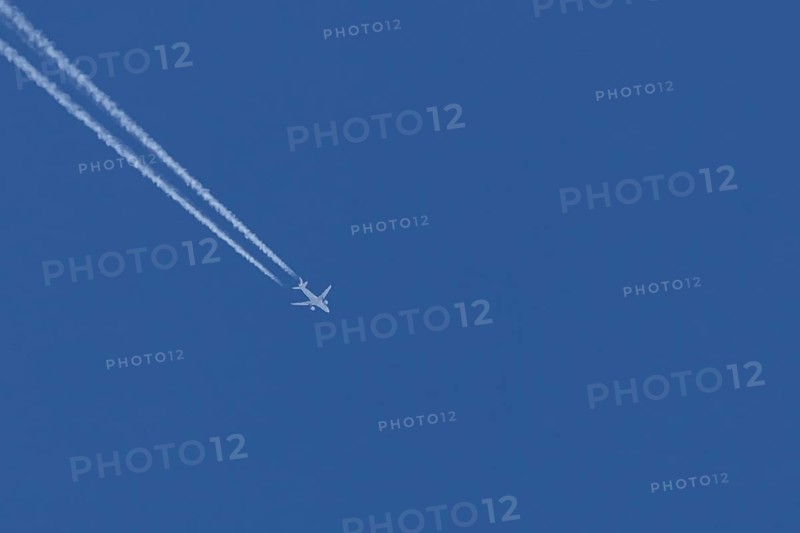 Airbus jet passenger aircraft flying in a blue sky with contrails or vapour trails behind, England, United Kingdom