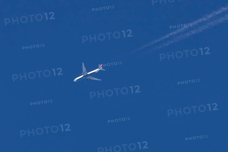 Boeing jet passenger aircraft of Delta airways airlines flying in a blue sky with contrails or vapour trails behind, England, United Kingdom