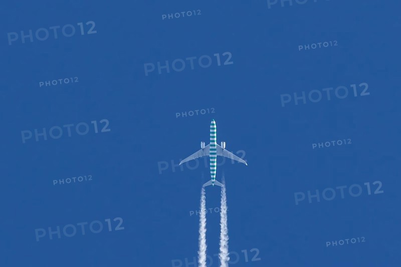 Boeing jet passenger aircraft flying in a blue sky with contrails or vapour trails behind, England, United Kingdom