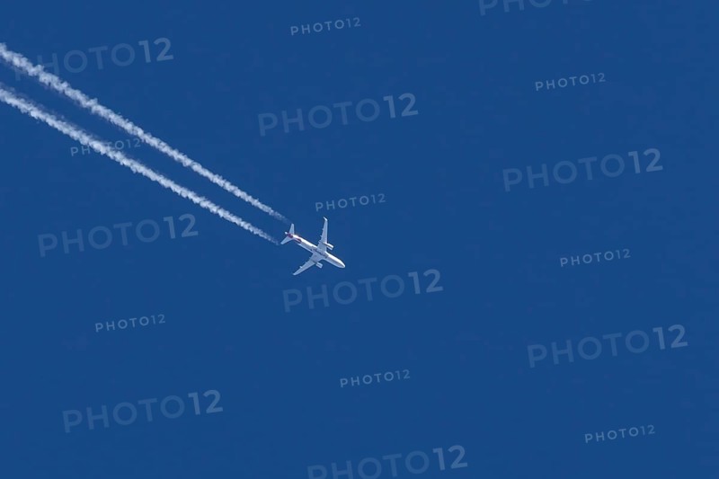 Airbus jet passenger aircraft of Eurowings airlines flying in a blue sky with contrails or vapour trails behind, England, United Kingdom