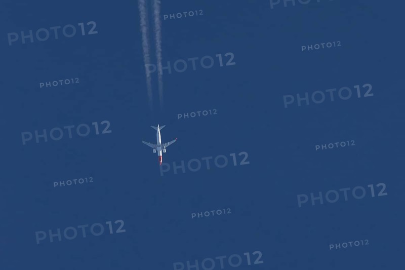 Boeing 737 jet passenger aircraft of Norwegian Air airlines flying in a blue sky with contrails or vapour trails behind, England, United Kingdom