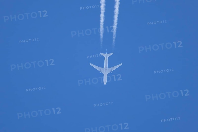Jet passenger aircraft flying in a blue sky with contrails or vapour trails behind, England, United Kingdom