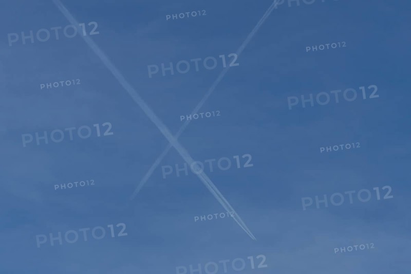 Aircraft contrails or vapour trails crossing in a blue sky, England, United Kingdom
