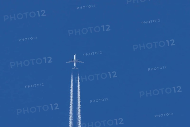 Airbus jet passenger aircraft of Kuwait airways flying in a blue sky with contrails or vapour trails behind, England, United Kingdom