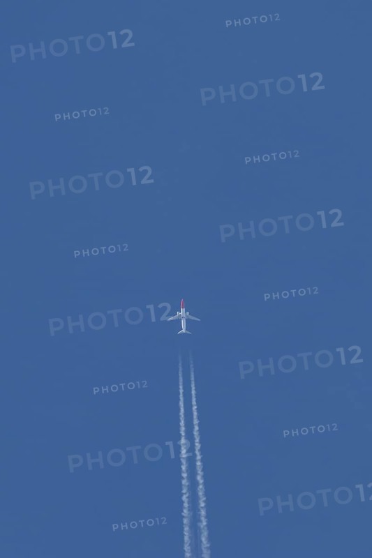 Boeing 737 jet passenger aircraft of Norwegian Air airlines flying in a blue sky with contrails or vapour trails behind, England, United Kingdom