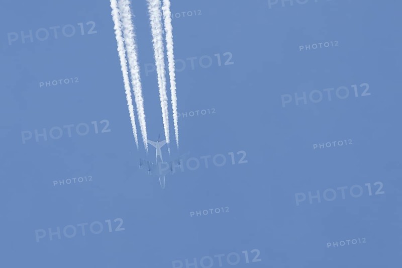 Boeing 747 jumbo jet passenger aircraft of Lufthansa airlines flying in a blue sky with contrails or vapour trails behind, England, United Kingdom