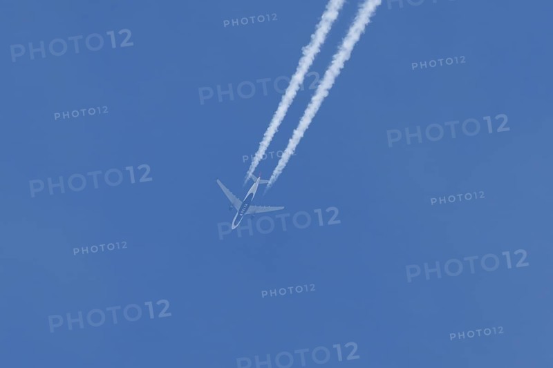 Jet passenger aircraft of Delta airlines flying in a blue sky with contrails or vapour trails behind, England, United Kingdom