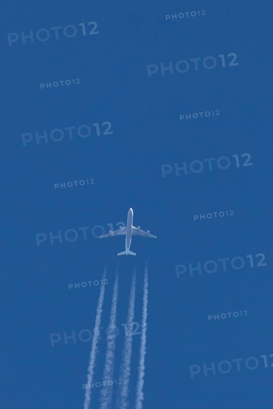 Jet commercial passenger aircraft flying in a blue sky with contrails or vapour trails behind, England, United Kingdom