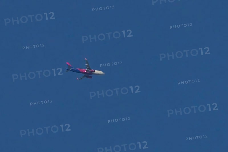 Airbus jet passenger aircraft of Wizz Air airlines flying in a blue sky, England, United Kingdom