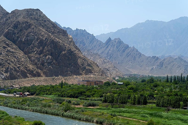 A green landscape with a river and mountains in the background, view of Iran, Aras River near Meghri, Syunik Province, Armenia
