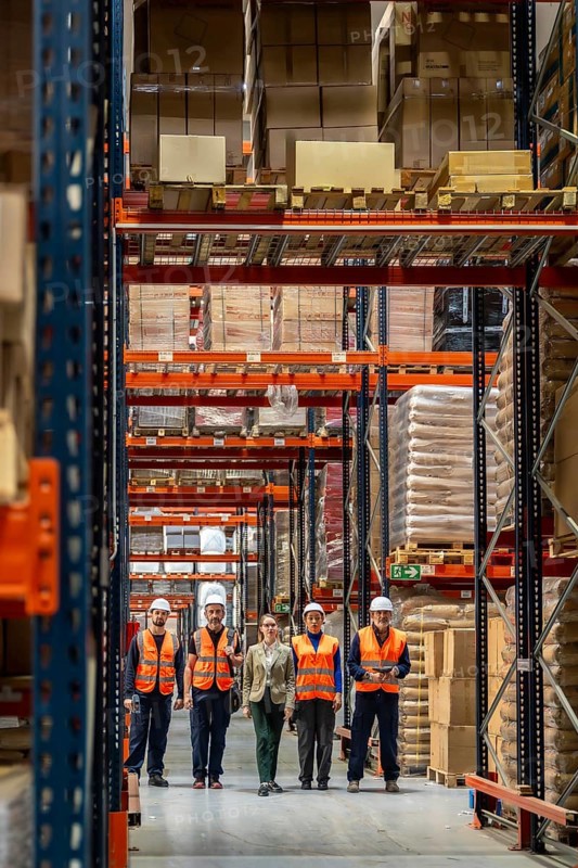 Diverse logistics team standing together in a large modern distribution warehouse, supervising inventory and operations within the shipping and receiving facility