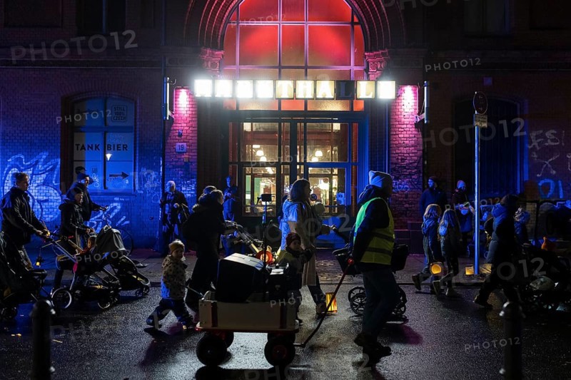 Participants with lanterns and strollers parade in front of the Arminiusmarkthalle during the lantern parade for Marting Day in Berlin Moabit on 11.11.2025