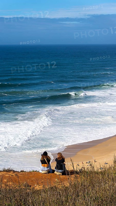 Tourists watch the waves of the Atlantic on the rocky plateau of Sito, also known as Forte São Miguel, a surfing paradise with monster waves in the months of November to February, Nazaré, Portugal