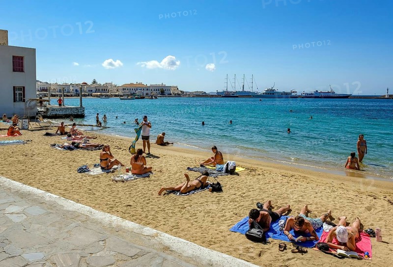 Mykonos, Cyclades, Greece - Tourists and locals like to bathe at the small town beach Paralia Cheras Mikonou right at the old port in the old town of Mykonos Town, Mykonos Chora. Mykonos is part of the Cyclades archipelago