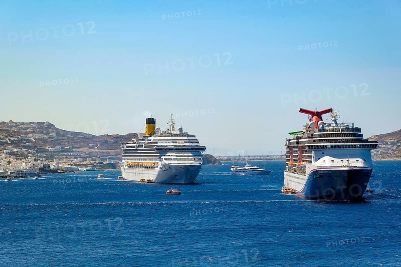 Mykonos, Cyclades, Greece - cruise ships CARNIVAL MIRACLE and COSTA FORTUNA are located in the bay off Mykonos City. Old town with windmills. Cruise ships bring tourists to shore