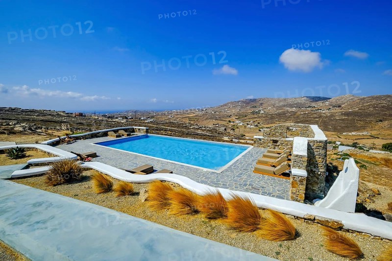 Ano Mera, Mykonos, Cyclades, Greece - Theme photo: vacation in Greece, sun loungers on the terrace of a boutique hotel with a sea view. Luxury hotel with swimming pool. Boutique Hotel Thronos Suites with views across the countryside towards the sea