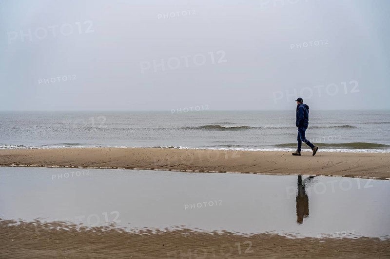 East beach of the East Frisian island of Spiekeroog, beach walk, man alone on the beach, at low tide, fog, calm of wind, tidal creek, Lower Saxony, Germany